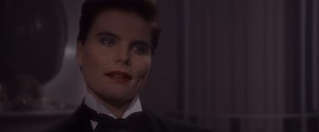 Movie still from “Sunset” (1988), directed by Blake Edwards – A woman in a suit and red lipstick looking to her left; Close Up shot, Over the shoulder angle