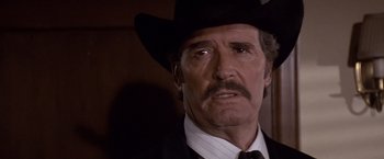 Movie still from “Sunset” (1988), directed by Blake Edwards – A man in a black hat and a black suit; Close Up shot, Low angle