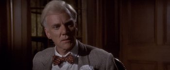 Movie still from “Sunset” (1988), directed by Blake Edwards – A man in a suit and bow tie looks to his left; Close Up shot, Over the shoulder angle