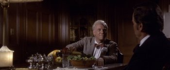 Movie still from “Sunset” (1988), directed by Blake Edwards – An older man sitting at a table with a bowl of vegetables; Medium shot, Over the shoulder angle
