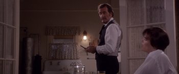 Movie still from “Sunset” (1988), directed by Blake Edwards – A man standing in front of a counter holding a cell phone; Medium shot, Low angle