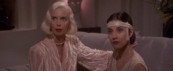 Movie still from “Sunset” (1988), directed by Blake Edwards – Two women in pink are posing for a picture; Close Up shot, Over the shoulder angle