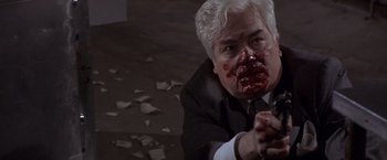 Movie still from “Sunset” (1988), directed by Blake Edwards – A man in a black suit with blood all over his face; Close Up shot, High angle
