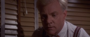 Movie still from “Sunset” (1988), directed by Blake Edwards – An older man in a suit and tie looking down; Close Up shot, Low angle