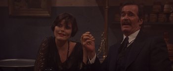 Movie still from “Sunset” (1988), directed by Blake Edwards – A man and a woman sitting next to each other holding hands; Close Up shot, High angle