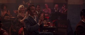 Movie still from “Sunset” (1988), directed by Blake Edwards – A group of people sitting around a table with pizza; Medium shot, Over the shoulder angle
