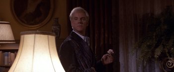 Movie still from “Sunset” (1988), directed by Blake Edwards – A man holding a pink flower in his hand; Medium shot, Over the shoulder angle