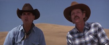 Movie still from “Sunset” (1988), directed by Blake Edwards – Two men in cowboy hats standing next to each other in the desert; Close Up shot, Low angle