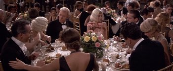 Movie still from “Sunset” (1988), directed by Blake Edwards – A group of people sitting at a table with flowers; Medium shot, High angle