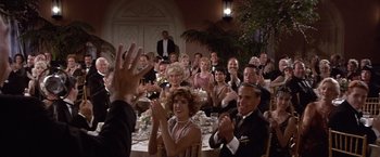 Movie still from “Sunset” (1988), directed by Blake Edwards – A group of people sitting at a table clapping and applauding; Wide shot, Over the shoulder angle