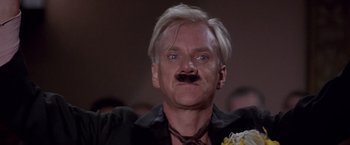 Movie still from “Sunset” (1988), directed by Blake Edwards – A person with a mustache wearing a black shirt; Close Up shot, Low angle