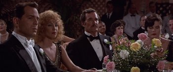 Movie still from “Sunset” (1988), directed by Blake Edwards – A group of people sitting at a dinner table; Medium shot, Over the shoulder angle