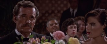 Movie still from “Sunset” (1988), directed by Blake Edwards – A group of people sitting around a table with flowers; Close Up shot, Over the shoulder angle