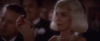 Movie still from “Sunset” (1988), directed by Blake Edwards – An older woman wearing a gold headpiece and a white wig; Close Up shot, Over the shoulder angle