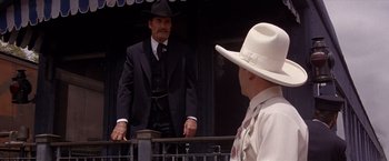 Movie still from “Sunset” (1988), directed by Blake Edwards – A man in a suit and a hat standing next to another man in a hat; Medium shot, Over the shoulder angle