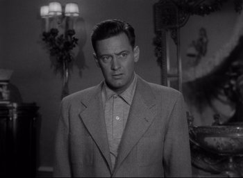 Movie still from “Sunset Blvd.” (1950), directed by Billy Wilder – A man wearing a suit and tie in a room; Close Up shot, Low angle