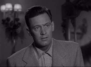 Movie still from “Sunset Blvd.” (1950), directed by Billy Wilder – A man in a suit and tie looking at the camera; Close Up shot, Low angle