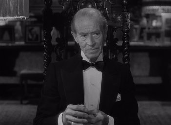 Movie still from “Sunset Blvd.” (1950), directed by Billy Wilder – An older man in a tuxedo sitting in a chair; Close Up shot, High angle