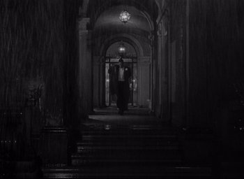 Movie still from “Sunset Blvd.” (1950), directed by Billy Wilder – A person walking down a set of stairs in a dark room; Extreme Wide shot, Low angle