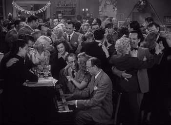 Movie still from “Sunset Blvd.” (1950), directed by Billy Wilder – A group of people gathered around a piano in a room; Wide shot, High angle