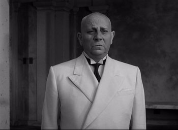 Movie still from “Sunset Blvd.” (1950), directed by Billy Wilder – A man in a suit and tie standing in front of a wall; Medium shot, Low angle