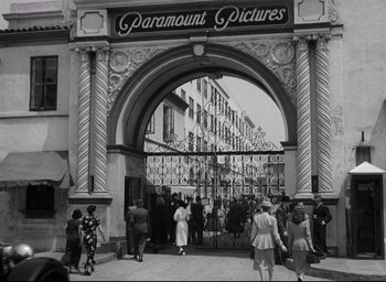 Movie still from “Sunset Blvd.” (1950), directed by Billy Wilder – A black - and - white photo of people walking on the sidewalk; Extreme Wide shot, Low angle