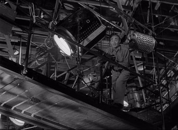 Movie still from “Sunset Blvd.” (1950), directed by Billy Wilder – A man sitting on a platform in a building; Wide shot, Low angle