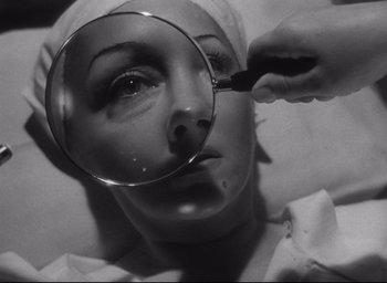 Movie still from “Sunset Blvd.” (1950), directed by Billy Wilder – A woman is looking through a magnifying glass; Close Up shot, Overhead angle