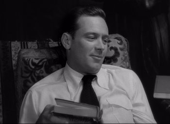 Movie still from “Sunset Blvd.” (1950), directed by Billy Wilder – A black and white photo of a man holding a book; Close Up shot, Low angle