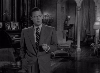 Movie still from “Sunset Blvd.” (1950), directed by Billy Wilder – A black and white photo of a man in a suit and tie; Medium shot, Over the shoulder angle