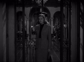 Movie still from “Sunset Blvd.” (1950), directed by Billy Wilder – A black and white photo of a woman standing in front of an iron gate; Medium shot, Low angle