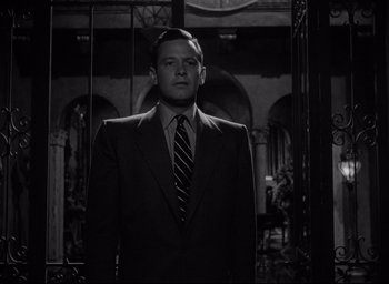 Movie still from “Sunset Blvd.” (1950), directed by Billy Wilder – A black and white photo of a man wearing a suit and tie; Medium shot, Low angle