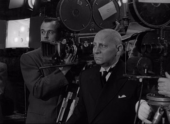 Movie still from “Sunset Blvd.” (1950), directed by Billy Wilder – A black and white photo of a man in a suit and tie; Medium shot, Low angle