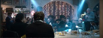 Movie still from “Suntan” (2016), directed by Argyris Papadimitropoulos – A group of people sitting at a table with plates of food; Wide shot, Over the shoulder angle