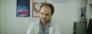 Movie still from “Suntan” (2016), directed by Argyris Papadimitropoulos – A person wearing a lab coat; Close Up shot, Low angle
