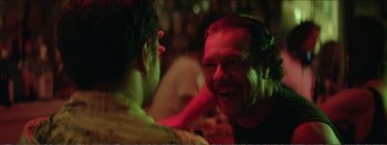 Movie still from “Suntan” (2016), directed by Argyris Papadimitropoulos – A man smiling at another man in a bar; Close Up shot, Over the shoulder angle