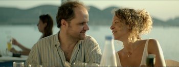 Movie still from “Suntan” (2016), directed by Argyris Papadimitropoulos – A man and a woman sitting next to each other at a table; Close Up shot, Low angle