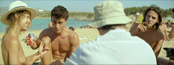 Movie still from “Suntan” (2016), directed by Argyris Papadimitropoulos – A man sitting on the beach looking at another man; Medium shot, Over the shoulder angle
