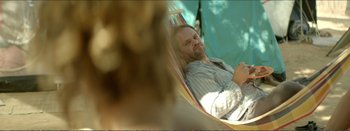 Movie still from “Suntan” (2016), directed by Argyris Papadimitropoulos – A man sitting in a hammock looking at the camera; Medium shot, Over the shoulder angle