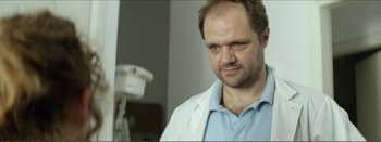 Movie still from “Suntan” (2016), directed by Argyris Papadimitropoulos – A person wearing a lab coat; Close Up shot, Low angle