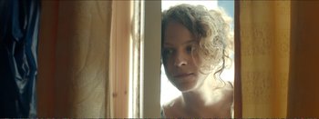 Movie still from “Suntan” (2016), directed by Argyris Papadimitropoulos – A woman with curly hair looking out of a window; Close Up shot, Low angle