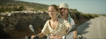 Movie still from “Suntan” (2016), directed by Argyris Papadimitropoulos – A man and a woman are riding a motorcycle together; Medium shot, Low angle