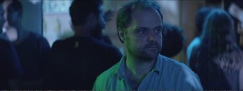 Movie still from “Suntan” (2016), directed by Argyris Papadimitropoulos – A person in a green light; Close Up shot, Over the shoulder angle