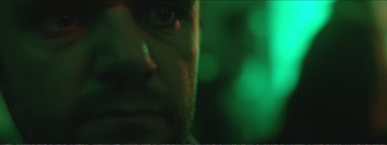 Movie still from “Suntan” (2016), directed by Argyris Papadimitropoulos – A man's face in green light; Extreme Close Up shot, Low angle
