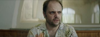 Movie still from “Suntan” (2016), directed by Argyris Papadimitropoulos – A person wearing a floral shirt; Close Up shot, Over the shoulder angle
