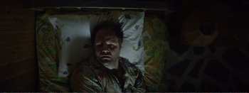 Movie still from “Suntan” (2016), directed by Argyris Papadimitropoulos – A man laying in a bed with a blanket on top of him; Medium shot, Overhead angle