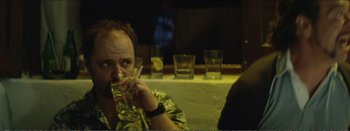 Movie still from “Suntan” (2016), directed by Argyris Papadimitropoulos – A man sitting at a table drinking a glass of water; Close Up shot, Over the shoulder angle