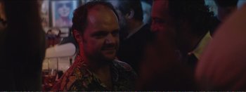Movie still from “Suntan” (2016), directed by Argyris Papadimitropoulos – A man in a hawaiian shirt is looking at the camera; Close Up shot, Over the shoulder angle