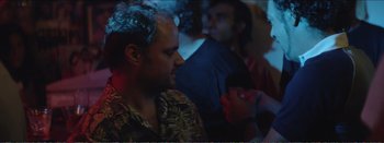 Movie still from “Suntan” (2016), directed by Argyris Papadimitropoulos – A man in a hawaiian shirt is looking at a cell phone; Close Up shot, Over the shoulder angle