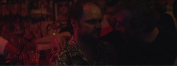 Movie still from “Suntan” (2016), directed by Argyris Papadimitropoulos – A man in a hawaiian shirt is looking at the camera; Close Up shot, Over the shoulder angle